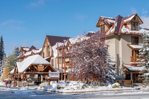 A lodge with a traditional wooden exterior, a covered entrance, and a sign indicating it is a ski resort. - Mountain Lodge Room | Steps to Downtown Banff (Banff)