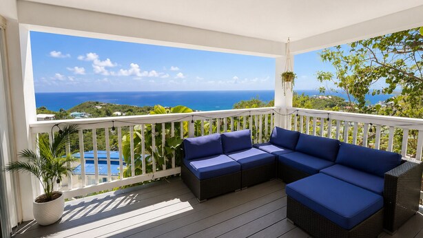 A balcony with a white railing, a blue sofa, and a hanging plant.