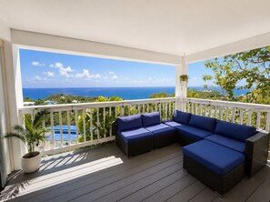 Un balcon avec une balustrade blanche, un canapé bleu et une plante suspendue.
