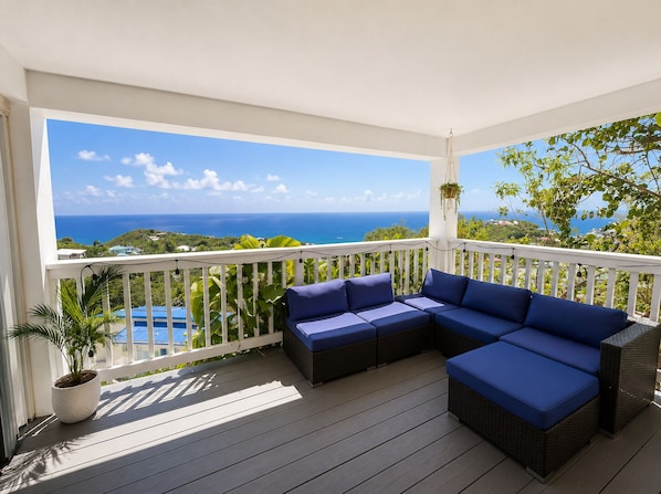 A balcony with a white railing, a blue sofa, and a hanging plant.