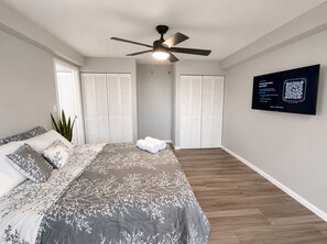 Ein Schlafzimmer mit Bett, Deckenventilator, Fernseher und einem QR-Code an der Wand.