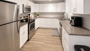 A modern kitchen with white cabinets, stainless steel appliances, and a granite countertop.