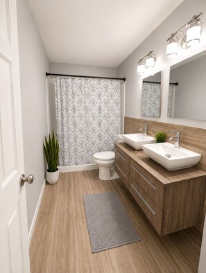 A modern bathroom with a wooden vanity, two sinks, a toilet, a shower curtain with a geometric pattern, and a potted plant.