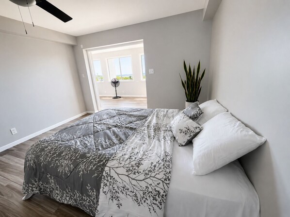Une chambre Ă coucher avec un lit, une plante en pot et une vue sur lâextĂ©rieur.