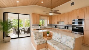 Una cocina moderna con armarios de madera, una isla integrada con asientos y vistas a un patio exterior.