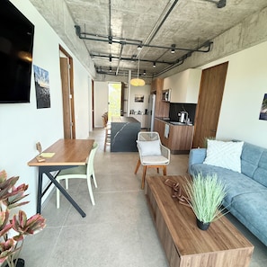 A modern living room with a dining area, kitchen, and a view of the outdoors.