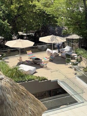 A rooftop patio with outdoor seating, umbrellas, and a fire pit.