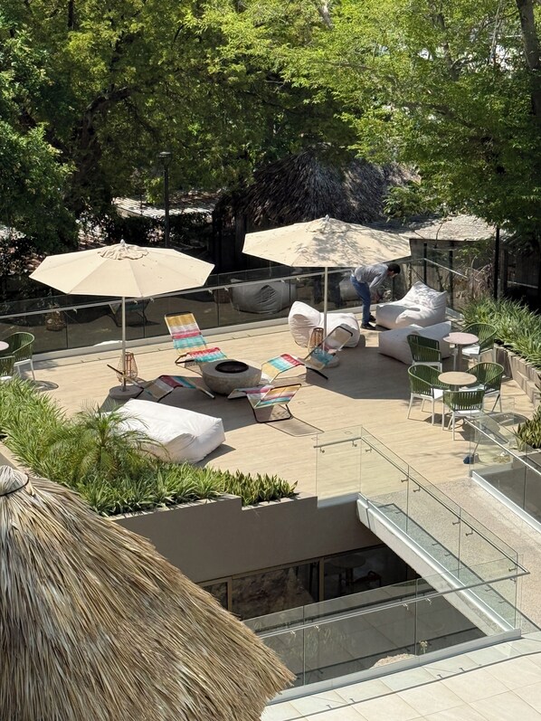 A rooftop patio with outdoor seating, umbrellas, and a fire pit.