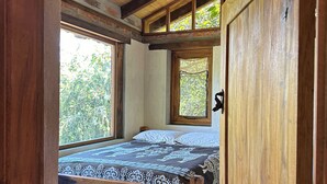 Una habitación de madera con una cama, una ventana y una puerta.