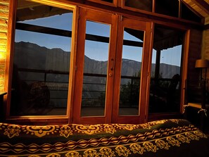 Ein Zimmer mit großem Fenster, Holztüren und einem gemusterten Teppich.