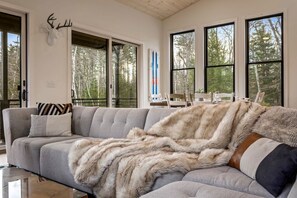Uma sala de estar moderna com um sofá seccional, um cobertor de pele e um chifre de veado fixado na parede.