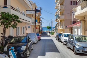 Una calle estrecha bordeada de coches aparcados y edificios.