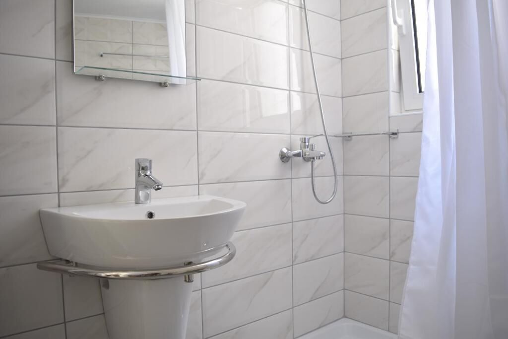A bathroom with a white sink, a mirror, and a shower.
