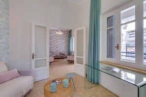Ein Zimmer mit einer Couch, einem runden Tisch, einer Glasschrank und Blick durch ein Fenster.