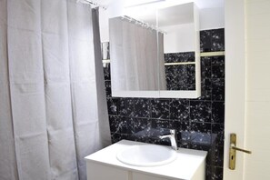 A bathroom with a white sink, black marble tiles, a shower curtain, and a mirror. - Samouil Apartment - Near Beach  (Chania)