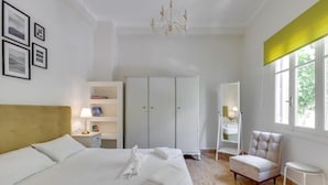 Ett hotellrum med en säng, en garderob, en stol, ett litet bord och ett fönster.