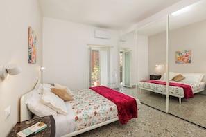Ein Schlafzimmer mit Bett, Nachttisch, Spiegel und Fenster.