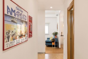 Ein Flur mit einem gerahmten Filmplakat, einem blauen Sofa, einer Topfpflanze und einer Holztür.