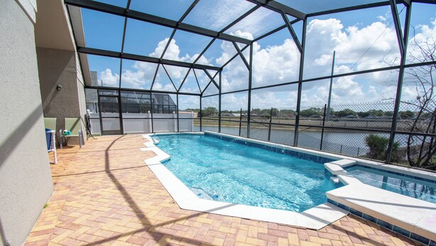 En swimmingpool med en uteplats i tegel, ett överbyggt område och utsikt över himlen och molnen.