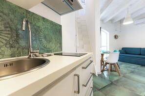 Eine moderne Küche mit einer Edelstahl-Spüle, einer weißen Arbeitsplatte und einer Rückwand mit grünem Muster.