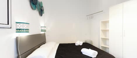 A hotel room with a bed, a wardrobe, a bedside table, and decorative wall art.