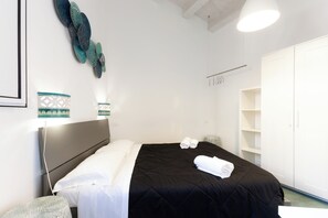 Habitación de hotel con cama, armario, mesita de noche y decoración mural.