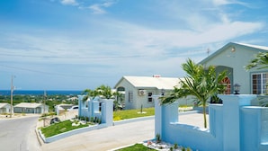 A residential area with houses, a clear sky, and a distant view of the ocean.