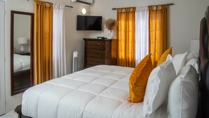 A hotel room with a bed, a dresser, a television, and an air conditioning unit.