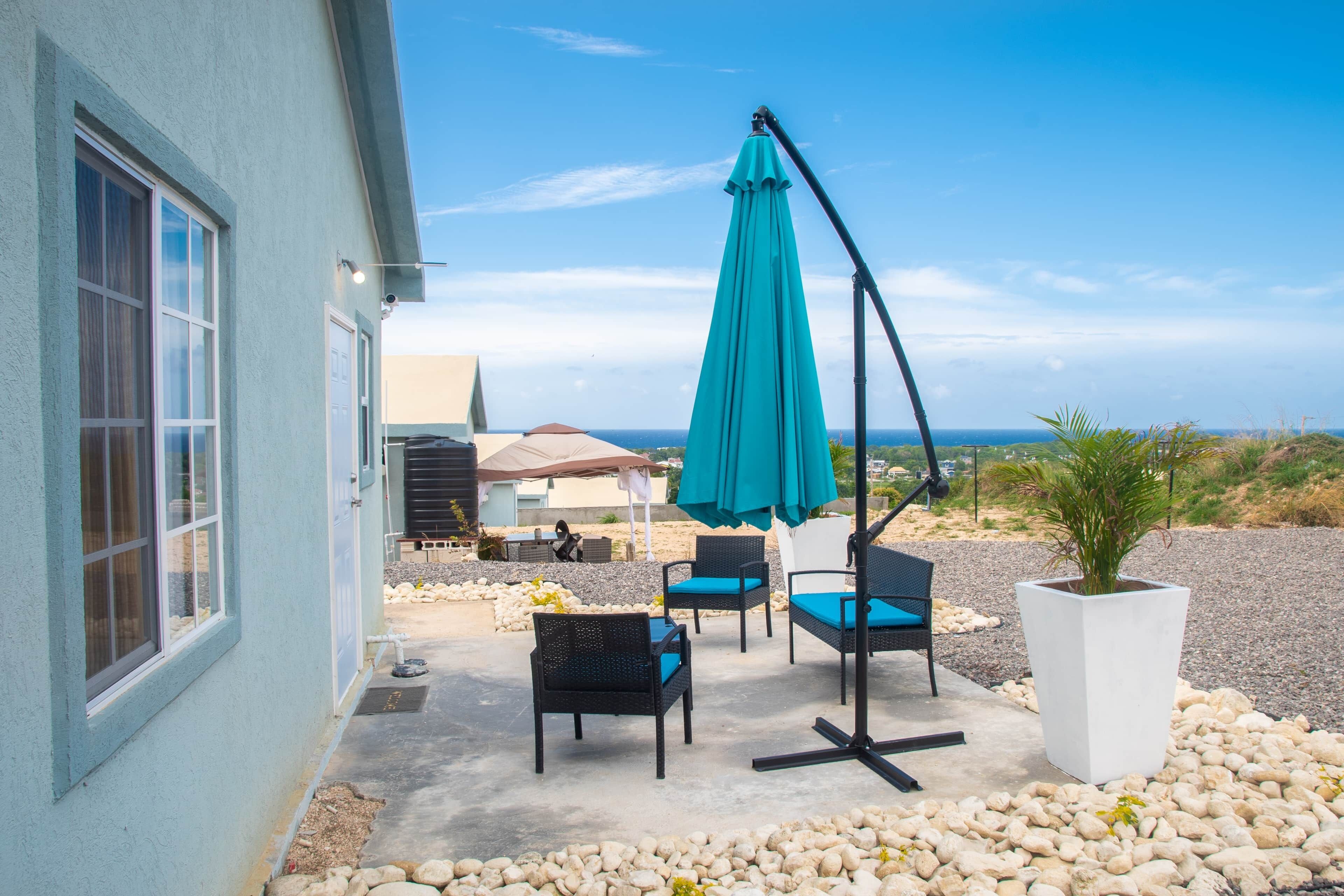 Un patio con mobiliario exterior, una planta en maceta y vista al océano.