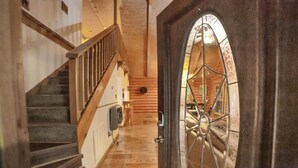Una escalera de madera que conduce al interior de una cabaña de troncos con una puerta grande y arqueada.