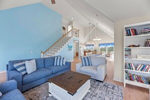 Ein geräumiges Wohnzimmer mit blauer Wand, einer Treppe, einem Bücherregal und einem Essbereich.