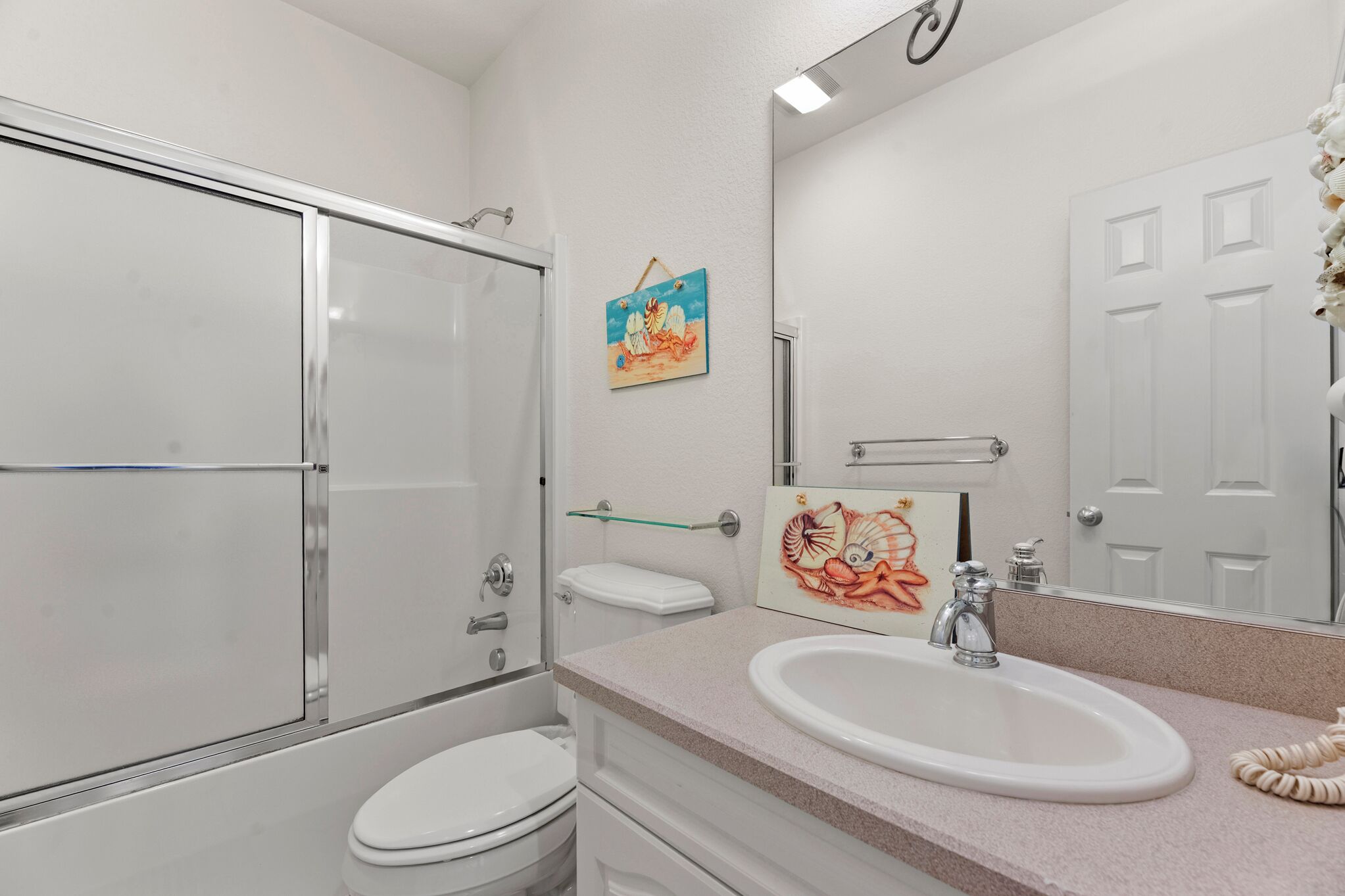 A bathroom with a shower, toilet, sink, and a mirror.