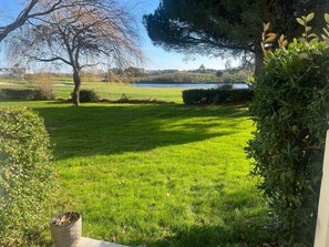 A well-maintained lawn with a large tree and a hedge in the foreground. - Le cosy du Green - free pool & golf (Talmont-Saint-Hilaire)