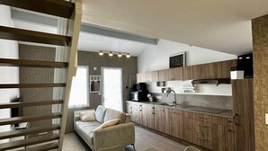 A modern kitchen with wooden cabinets, a dining table, and a sofa. - L'escapade du Maupas - house 5 min from the beach (La Tranche-sur-Mer)