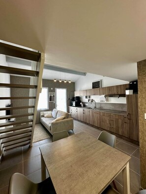 A modern kitchen with wooden cabinets, a dining table, and a sofa. - L'escapade du Maupas - house 5 min from the beach (La Tranche-sur-Mer)