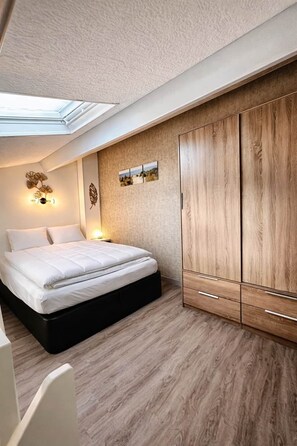 Una camera da letto con un letto, lampade sui comodini, un armadio e un lucernario.