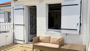 A patio with wicker furniture, a white wall, and a red-tiled roof. - L'escapade du Maupas - house 5 min from the beach (La Tranche-sur-Mer)