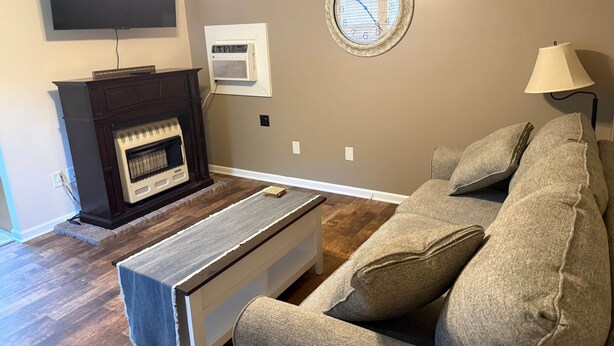 A living room with a fireplace, a flat-screen TV, a clock, and a sofa.