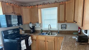 A kitchen with wooden cabinets, a black stove, a sink, and a toaster.