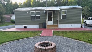 A single-story building with a gravel driveway, a fire pit, and a truck parked outside.