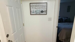 Un pasillo con piso de madera, una puerta blanca y un cartel en la pared.