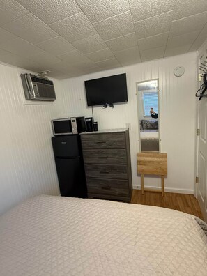 Ein Schlafzimmer mit einem Bett, einem Schminktisch, einem Fernseher und einem kleinen Tisch.