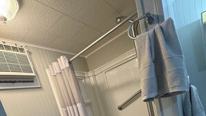 Un baño con ducha, bañera, toallero y rejilla de ventilación.