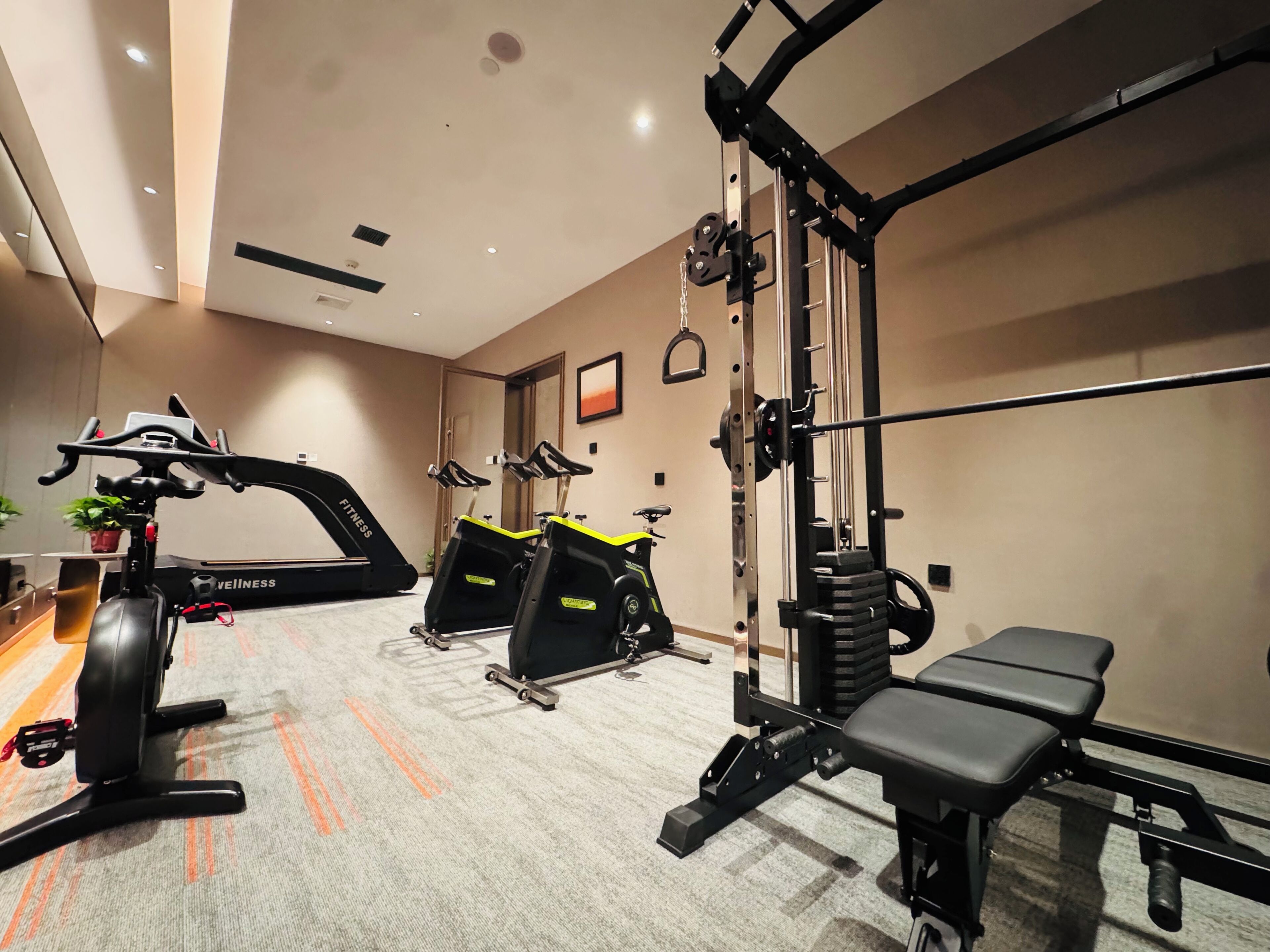 Ein Fitnessraum mit Trainingsgeräten, Laufband und Bank.