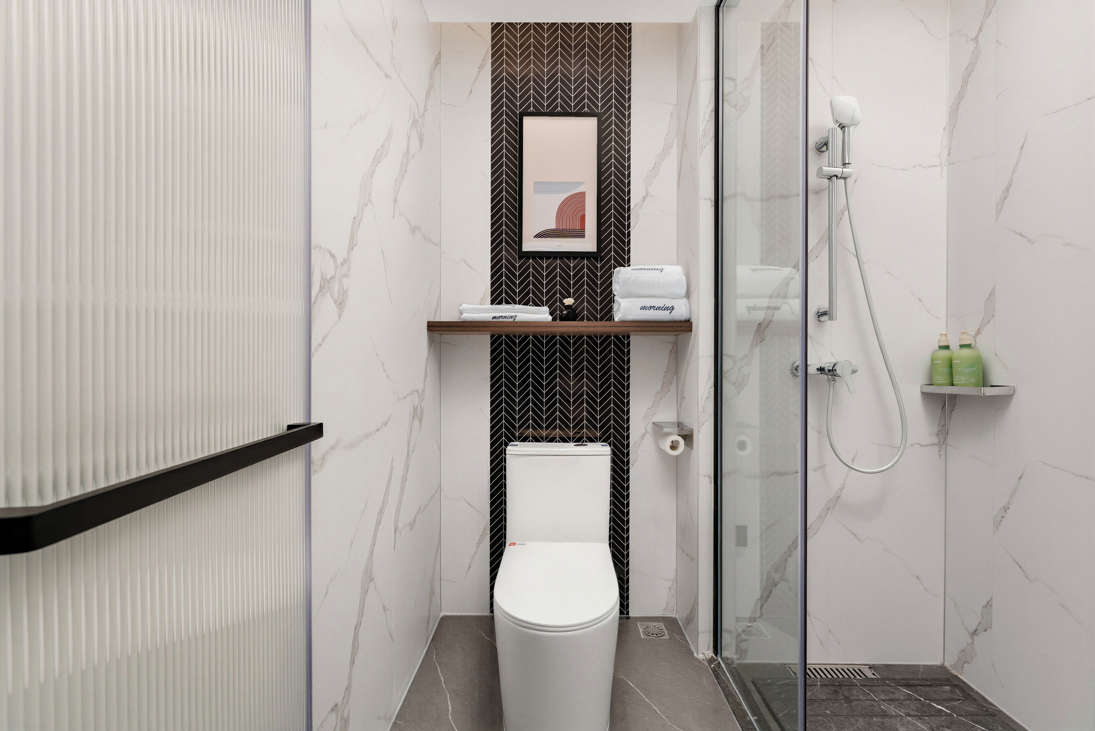 A modern bathroom with a toilet, shower, and marble walls.
