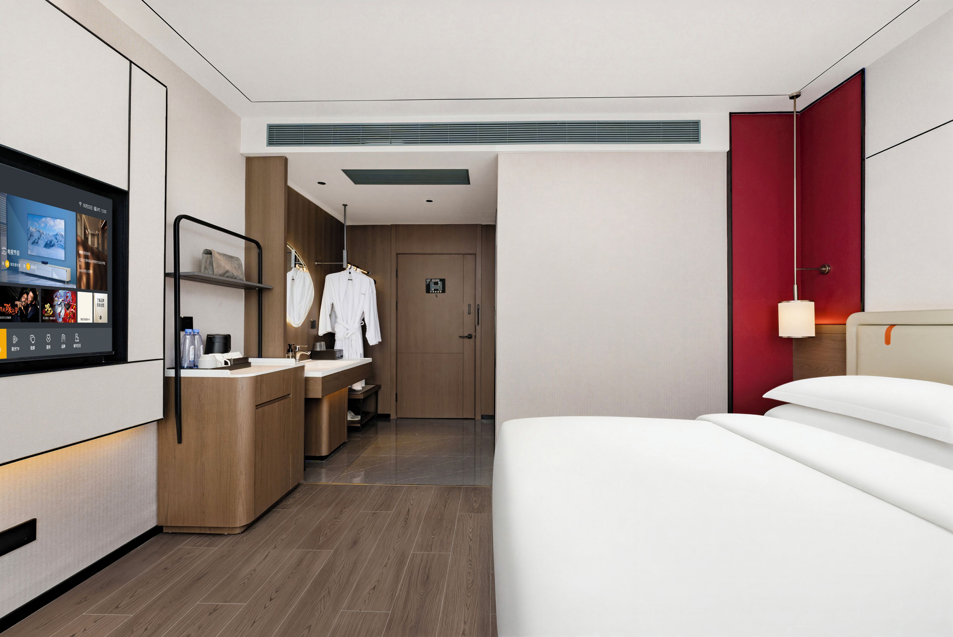 A modern hotel room with a bed, a TV, a desk with a computer, a mini-fridge, and a bathroom with a shower and toilet.