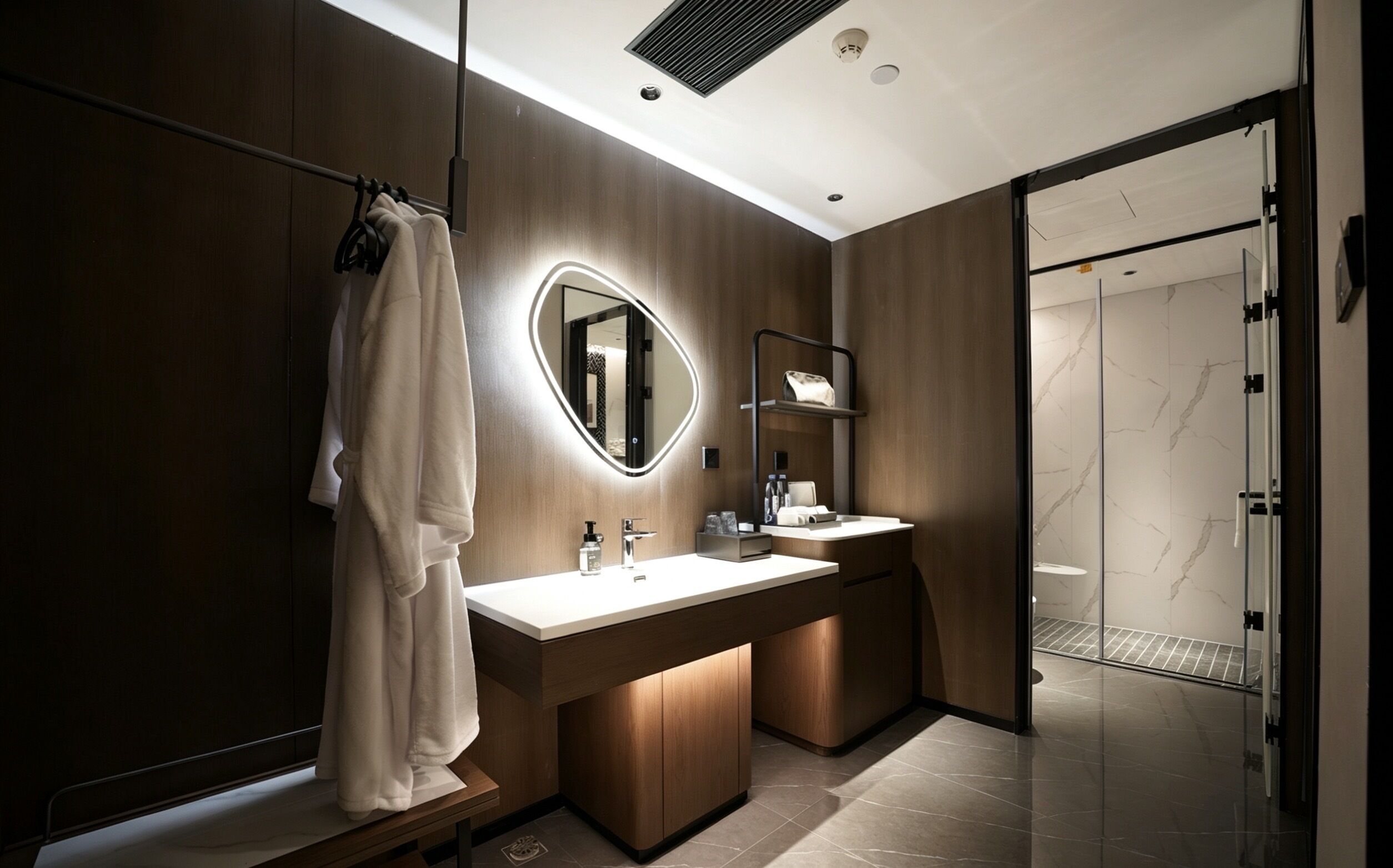 A modern bathroom with a large mirror, two sinks, a towel rack, and a glass shower enclosure.
