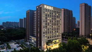 A high-rise hotel with a modern facade, multiple floors, and a well-lit entrance. - Morin Hotel (Zhengzhou)