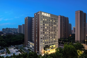 A high-rise hotel with a modern facade, multiple floors, and a well-lit entrance. - Morin Hotel (Zhengzhou)