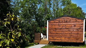 Una cabaña de madera con un camino de grava que la conduce, rodeada de follaje y árboles.